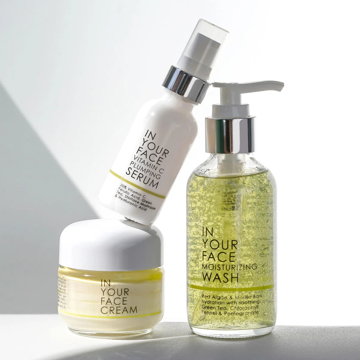 Set of skincare products including serum, cream, and wash with 'In Your Face' branding on a neutral background.