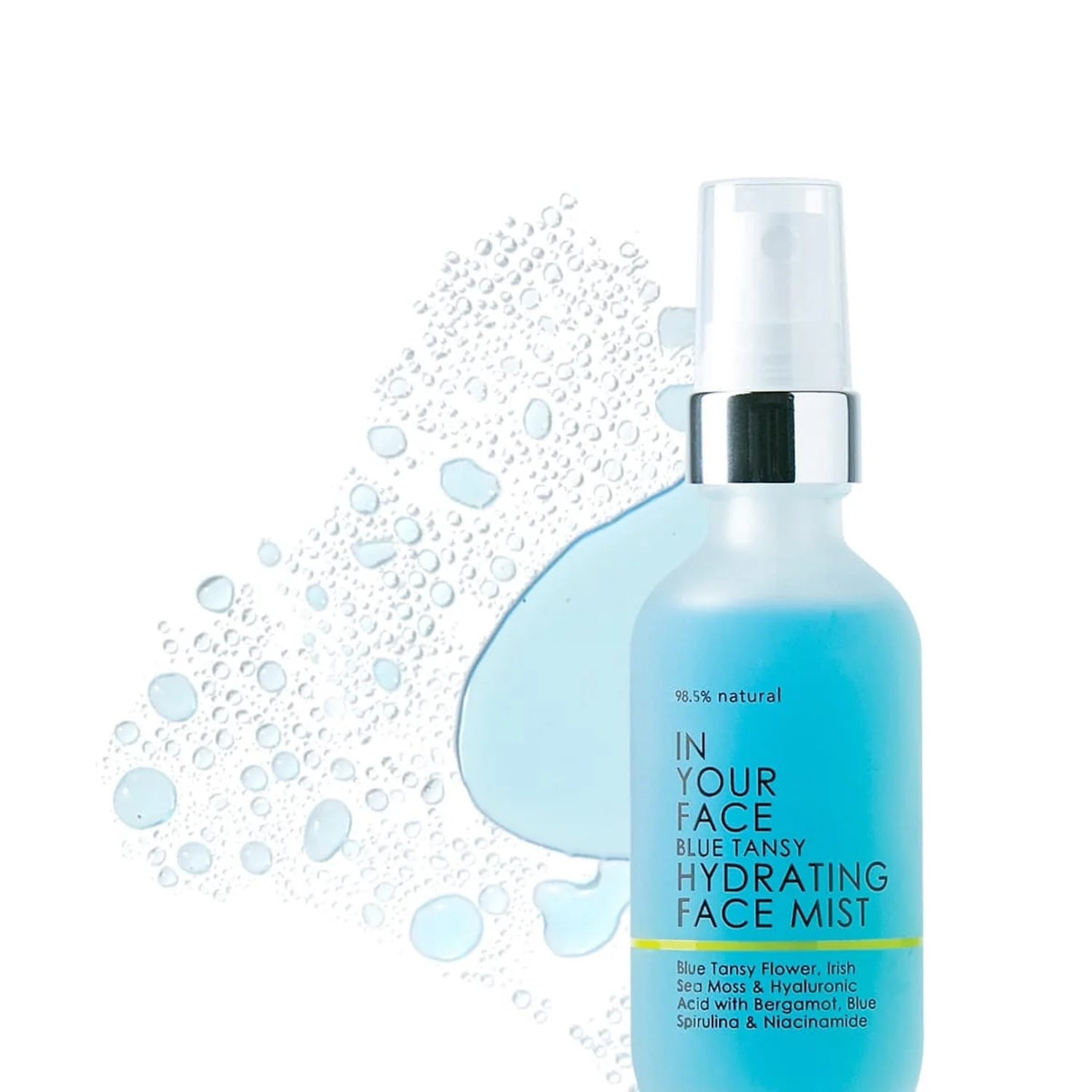 Spray bottle of In Your Face Blue Tansy Hydrating Face Mist surrounded by water droplets and blue liquid, emphasizing its lightweight, hydrating formula for glowing skin.