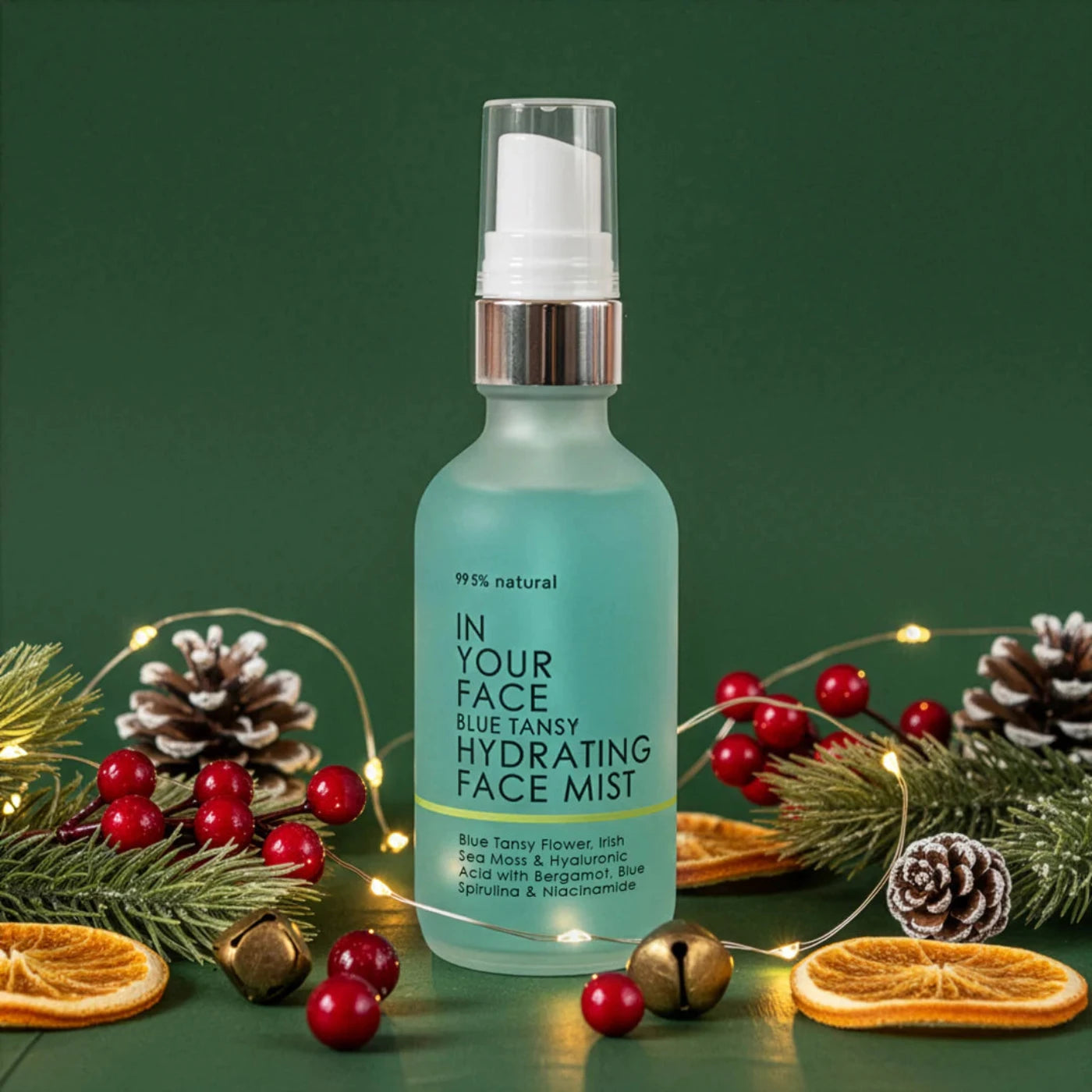 Hydrating face mist bottle with festive decorations on a green background