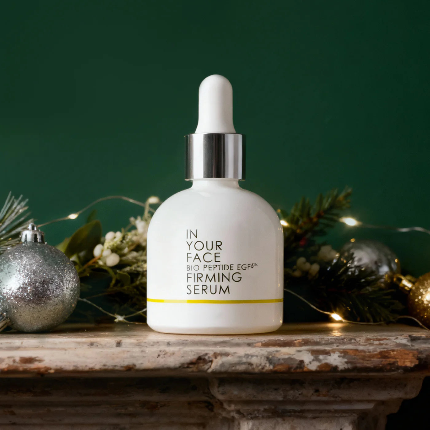 Skincare serum bottle labeled 'In Your Face' on a decorative surface with greenery and ornaments.
