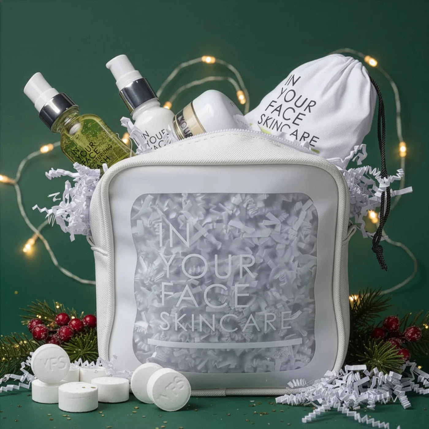 In Your Face Skincare products including bottles, a pouch, and tablets on a green background with decorative lights.