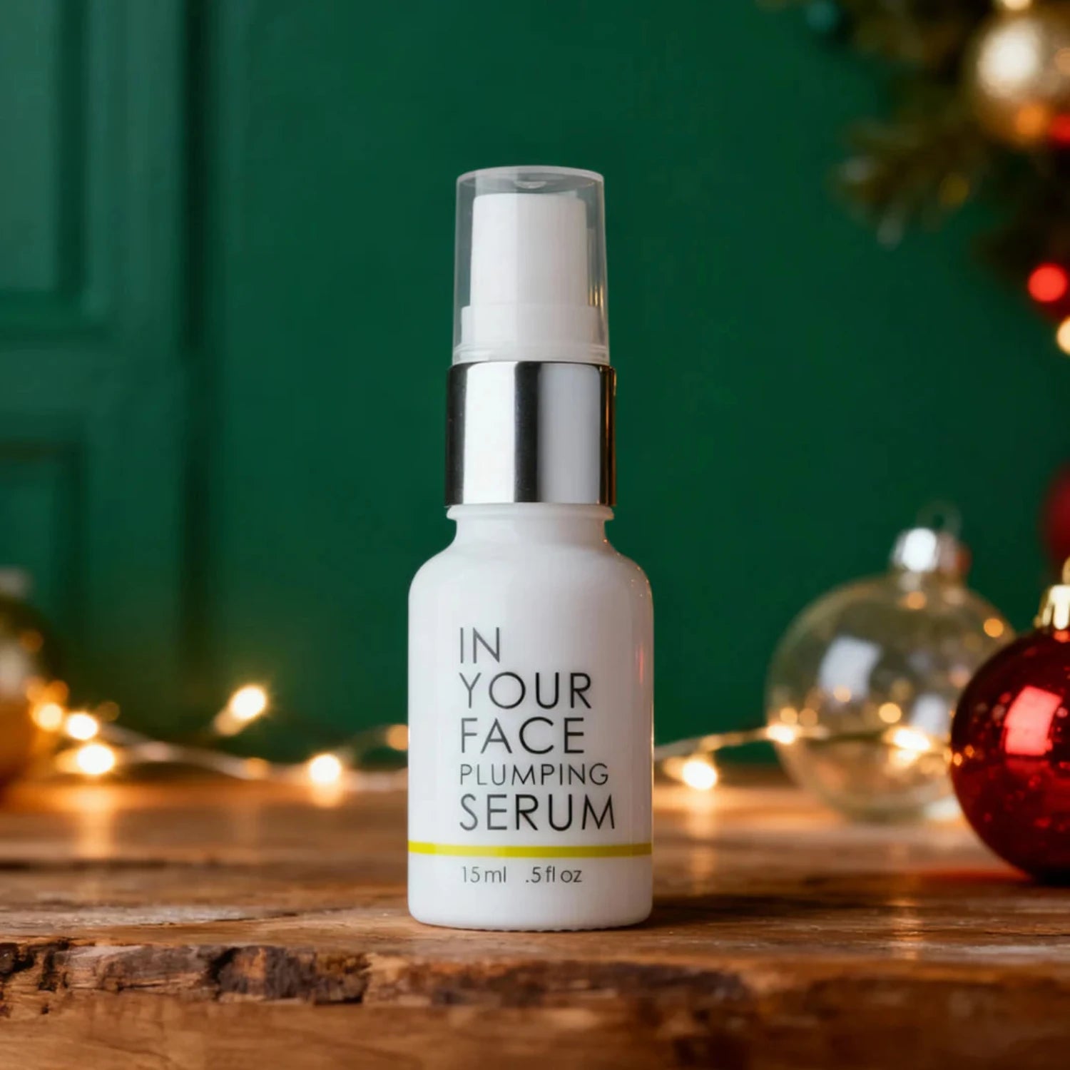 Plumping serum bottle on a wooden surface with festive decorations in the background