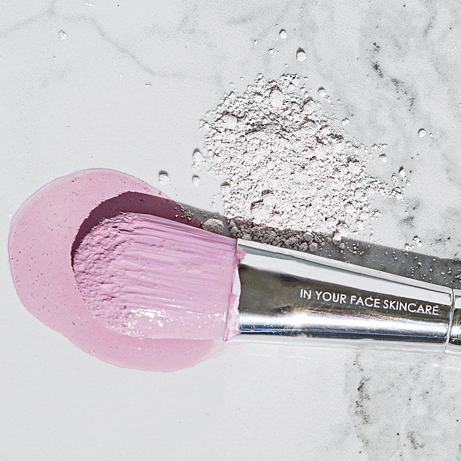 Close-up of the In Your Face Radiant Detox Mineral Mask applied on a skincare brush with mask powder and paste on a marble surface, highlighting its smooth, luxurious texture.