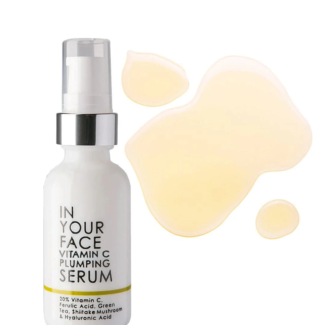 Vitamin C plumping serum bottle with serum droplets on a white background