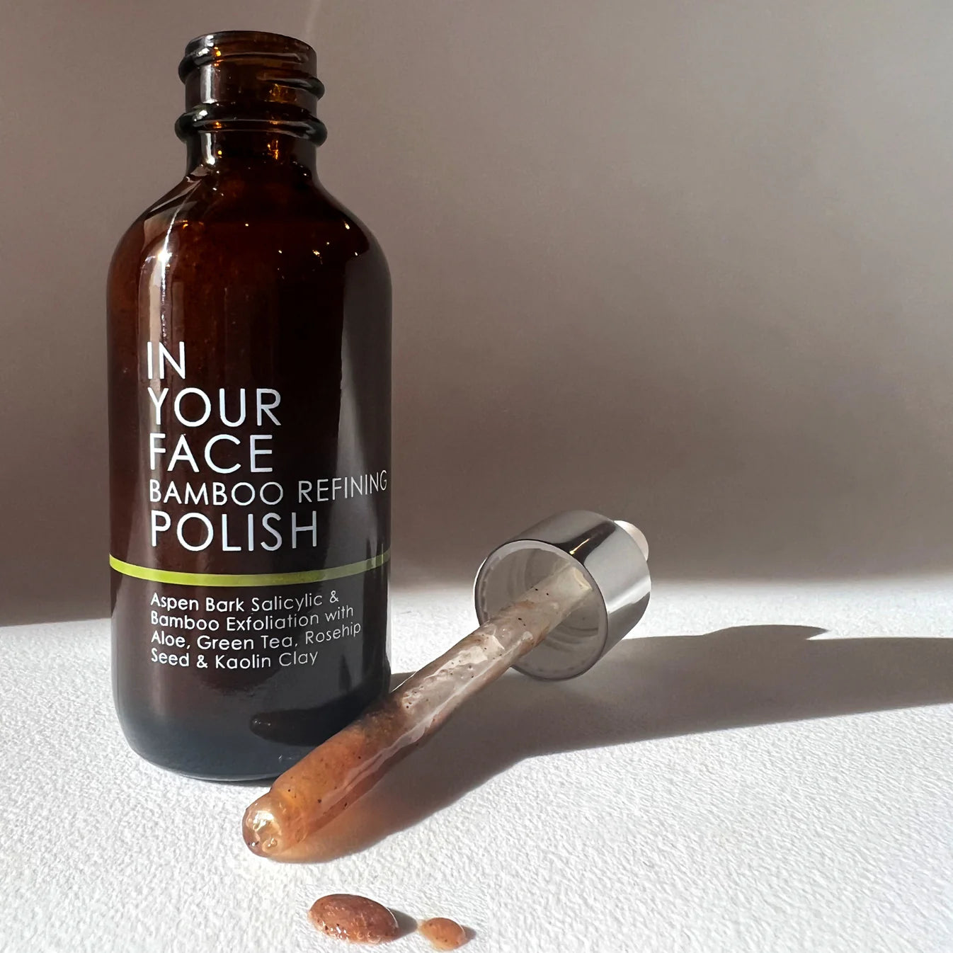 Brown bottle labeled 'In Your Face Bamboo Refining Polish' with a dropper on a light background