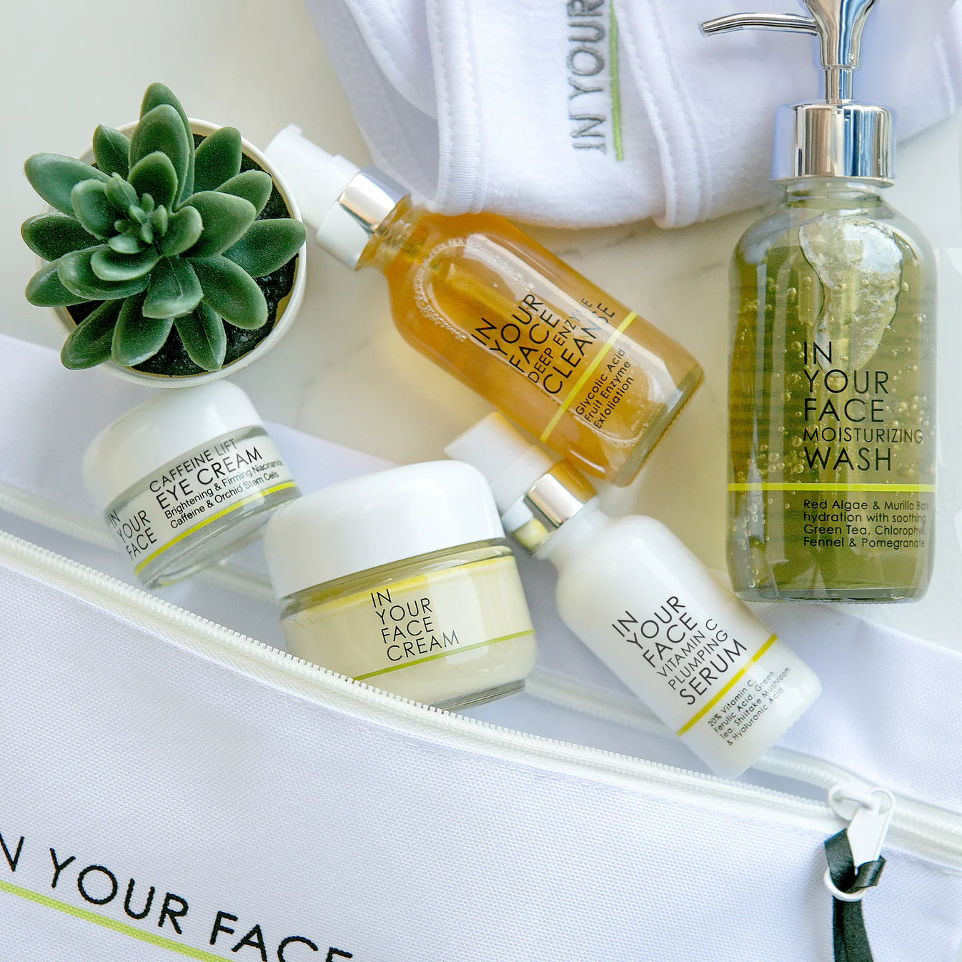 Collection of skincare products including bottles and jars on a white surface with 'IN YOUR FACE' branding.