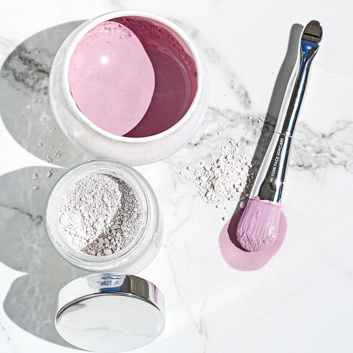 Cosmetic product with pink powder and a brush on a marble surface