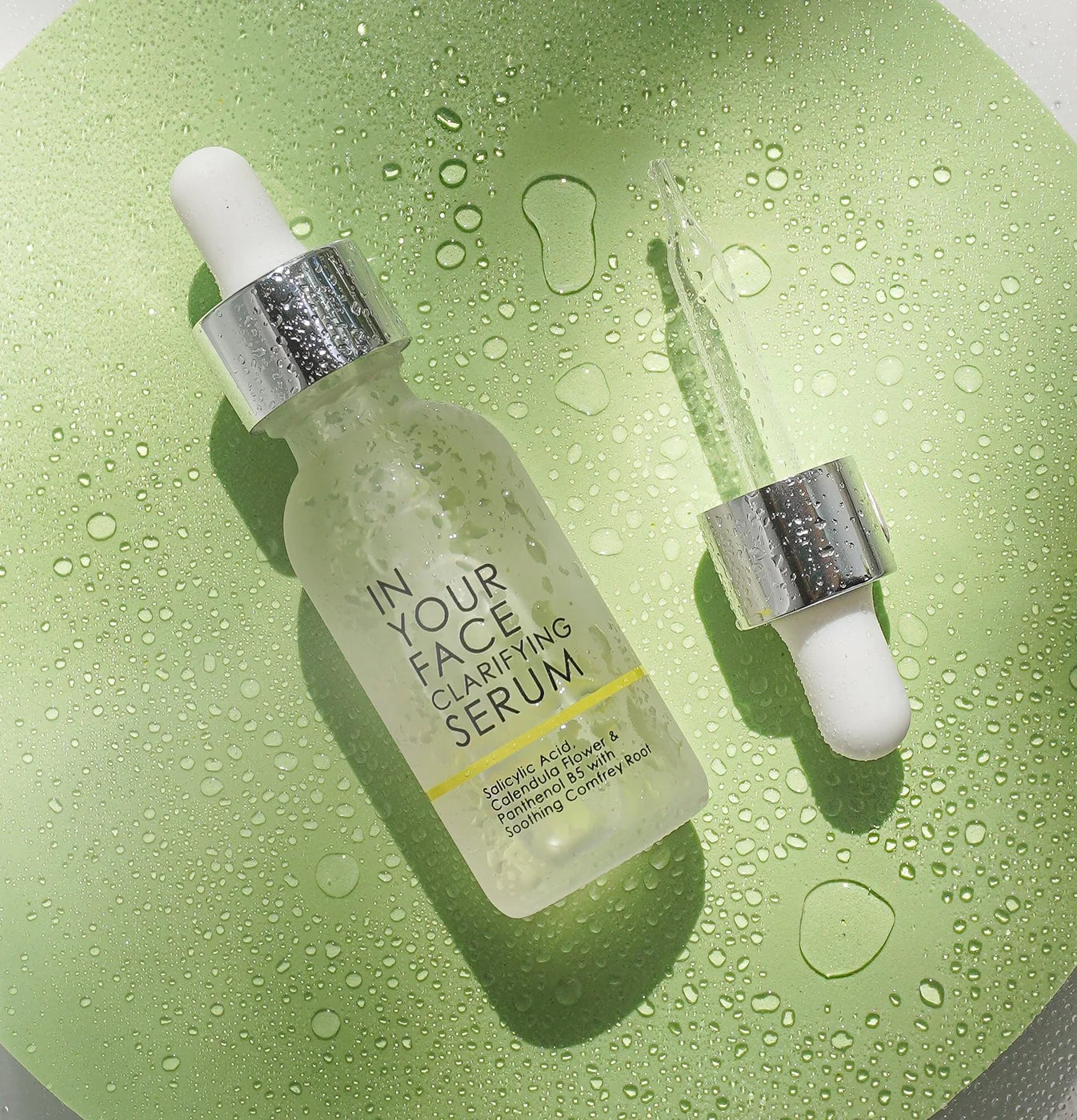 In Your Face Clarifying Serum bottle with dropper on green surface with water droplets – salicylic acid acne treatment serum