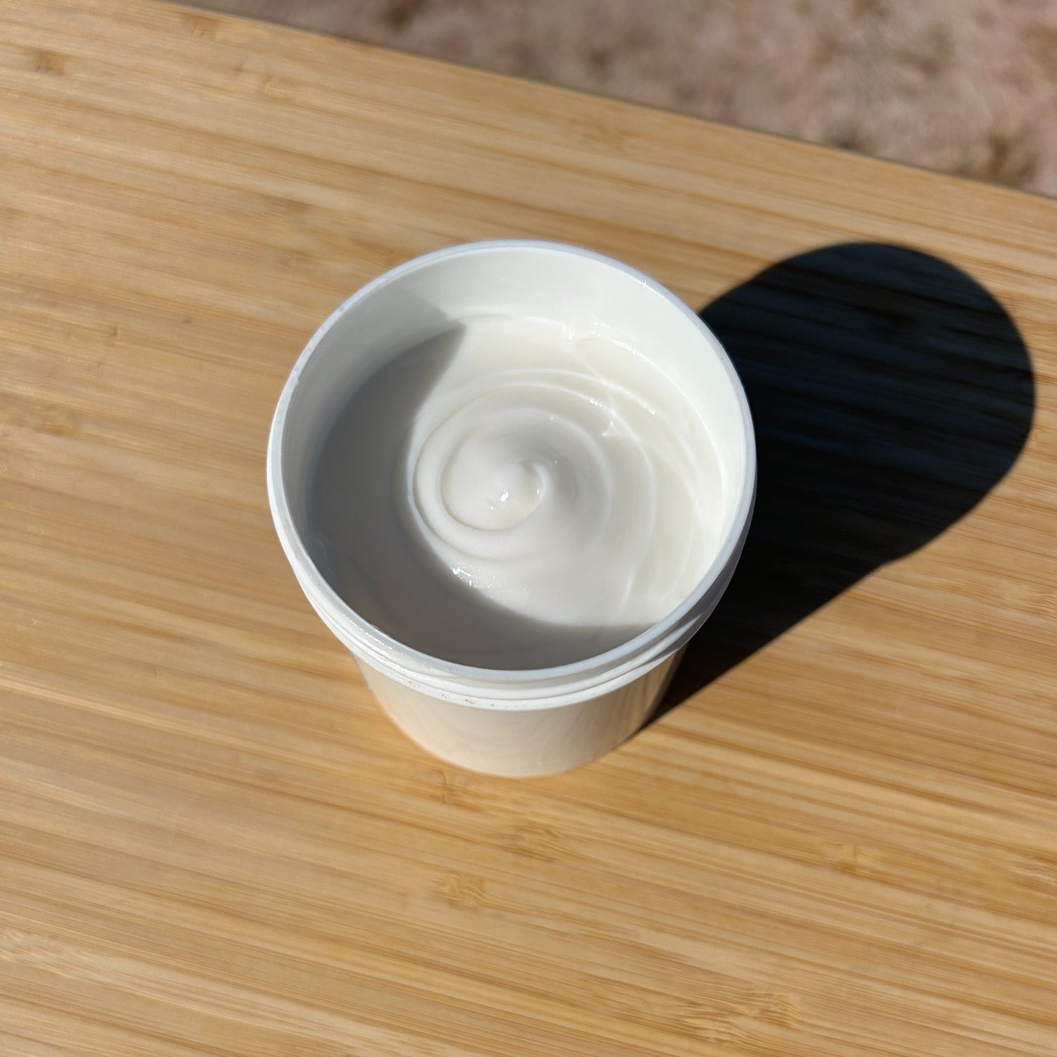 White cup with a swirl of cream on a wooden surface