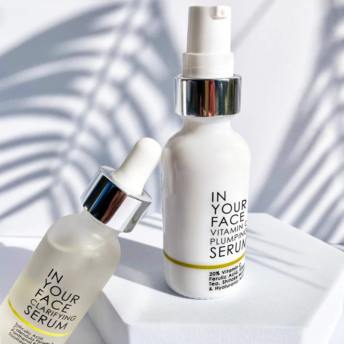 Two skincare serum bottles labeled 'In Your Face' on a light background with leaf shadows.