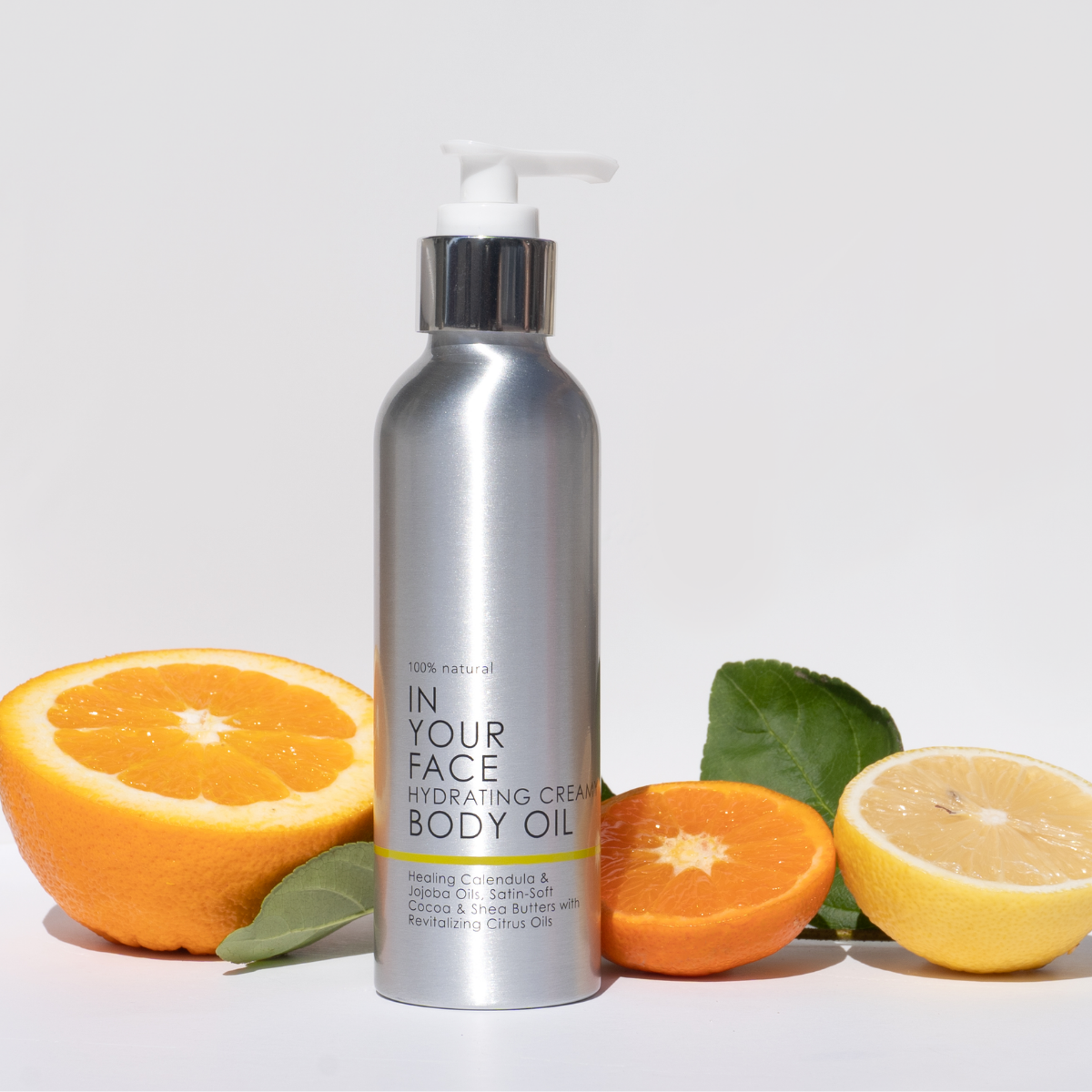 In Your Face Hydrating Creamy Body Oil in a sleek silver bottle with a pump, designed for nourishing and hydrating the skin with natural ingredients.