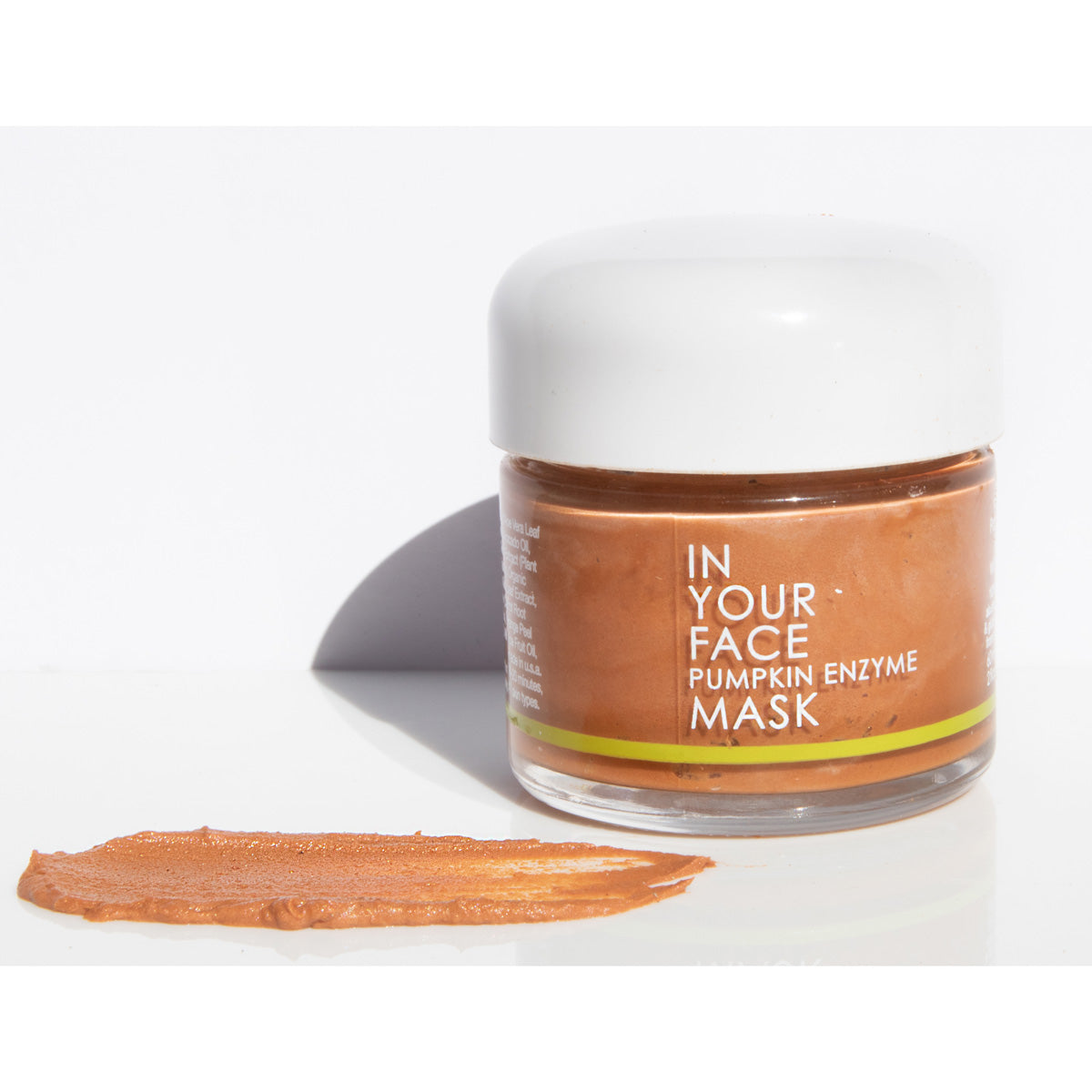 In Your Face Pumpkin Enzyme Mask in a small glass jar with a white lid, formulated to exfoliate and brighten the skin with pumpkin enzymes.