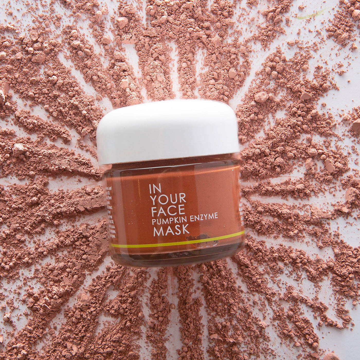 In Your Face Pumpkin Enzyme Mask in a small glass jar with a white lid, formulated to exfoliate and brighten the skin with pumpkin enzymes.