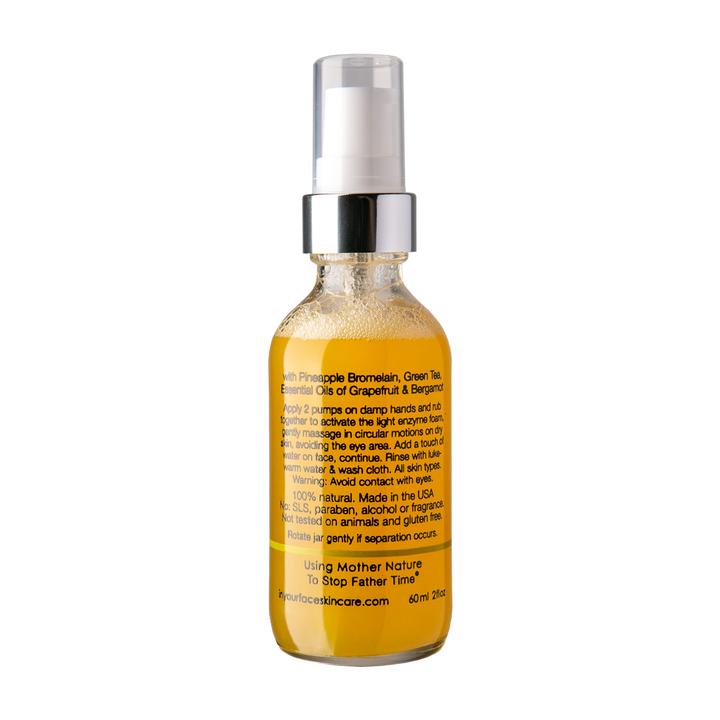Glass bottle of "In Your Face Deep Enzyme Cleanse" featuring glycolic acid and fruit enzyme exfoliation for deep cleansing.
