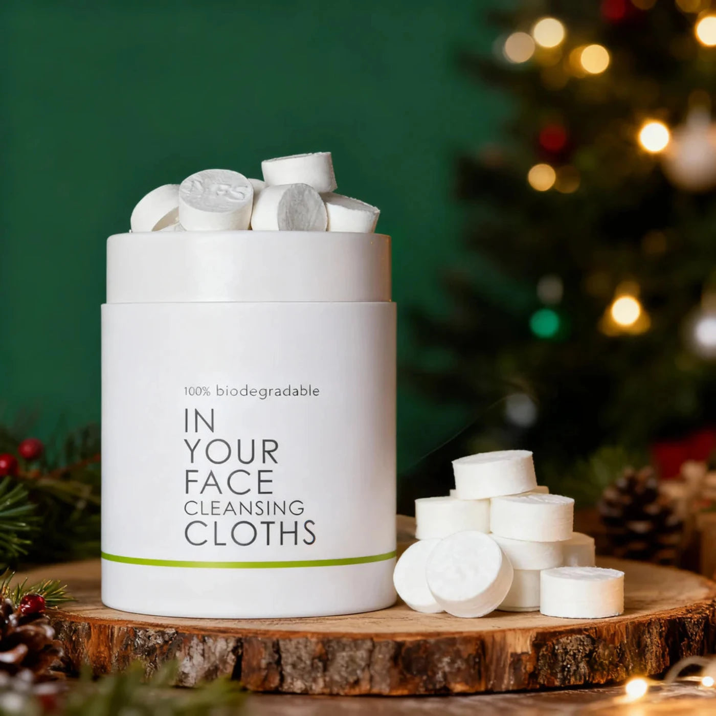 Container of biodegradable cleansing cloths on a wooden surface with a festive background.