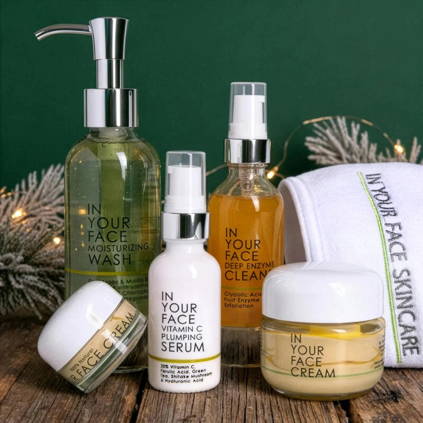 Collection of 'In Your Face' skincare products on a wooden surface with a green background.