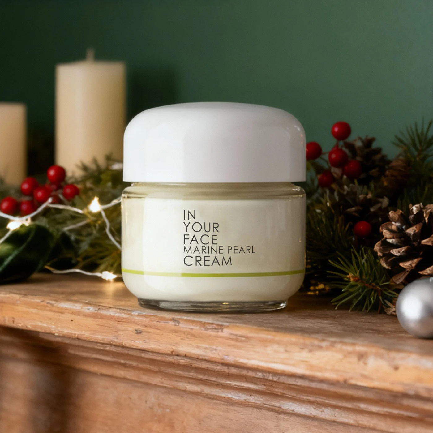 Jar of 'In Your Face Marine Pearl Cream' on a wooden surface with festive decorations in the background.