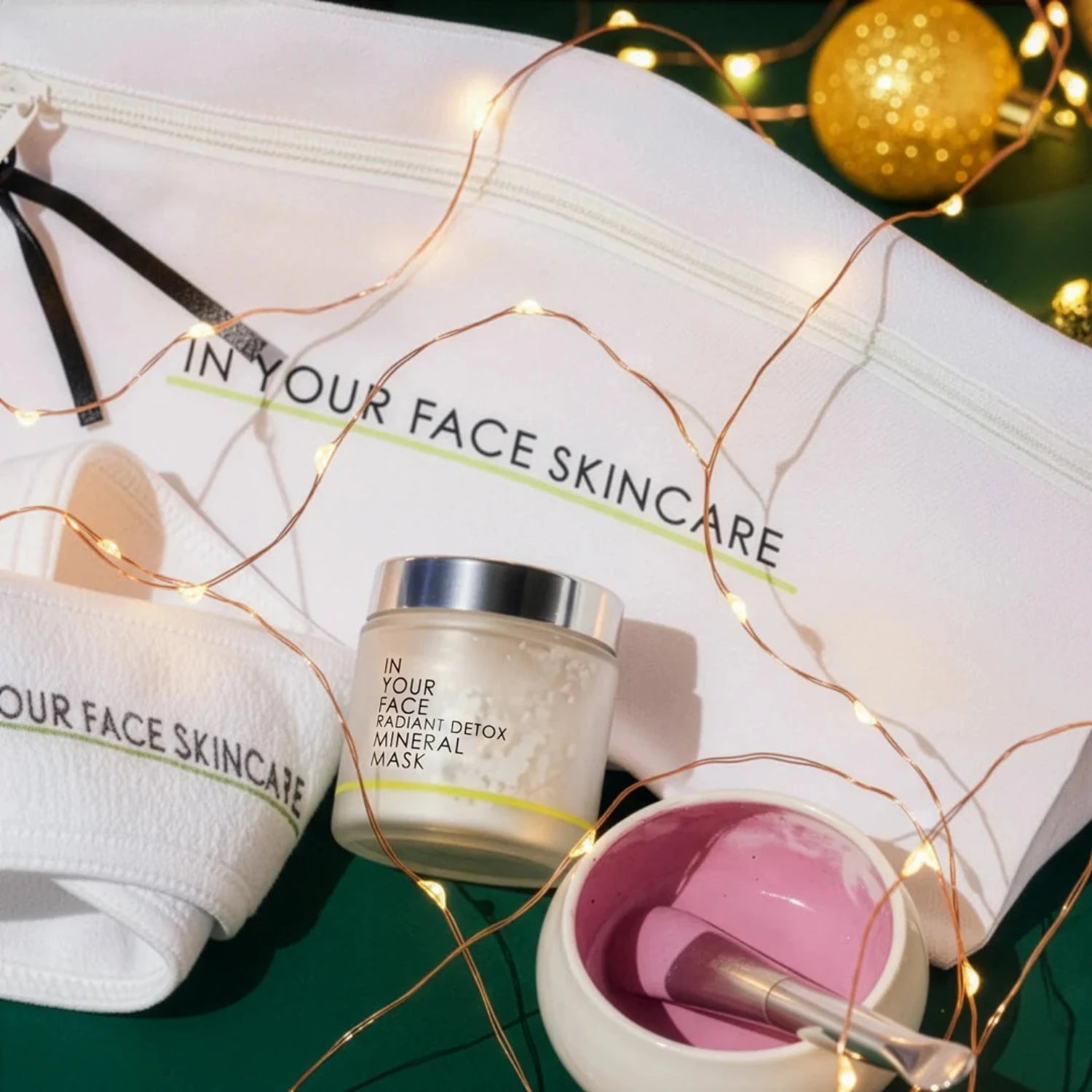 Skincare products with 'In Your Face Skincare' branding on a white surface with decorative lights.
