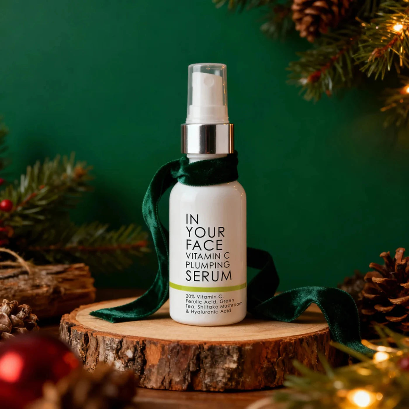 Vitamin C plumping serum bottle on a wooden surface with Christmas decorations.